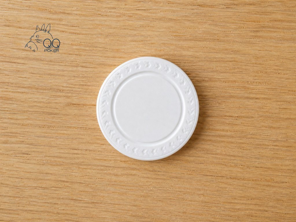 温暖浅橡木桌面上一枚白色圆形塑料庄家按钮，边缘压印花纹与中心凹槽清晰